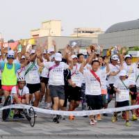 Home stretch: Tokyo Gov. Naoki Inose (without hat) reaches the goal with 101 other runners on Wednesday in Tokyo\'s Odaiba district. | YOSHIAKI MIURA