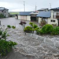 Low blow: Houses in Odate, Akita Prefecture, are flooded amid heavy downpours early Friday. | AKITA SAKIGAKE SHIMPO/KYODO