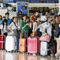 Outward bound: Holidaymakers heading to overseas destinations line up at the check-in counters at Narita airport Saturday as the Bon summer holidays began. | KYODO