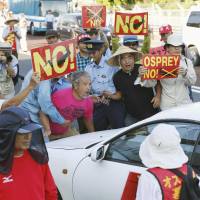 Up in arms: People block a U.S. military car outside Okinawa\'s Futenma base to protest Monday\'s Osprey ferry flights. | KYODO