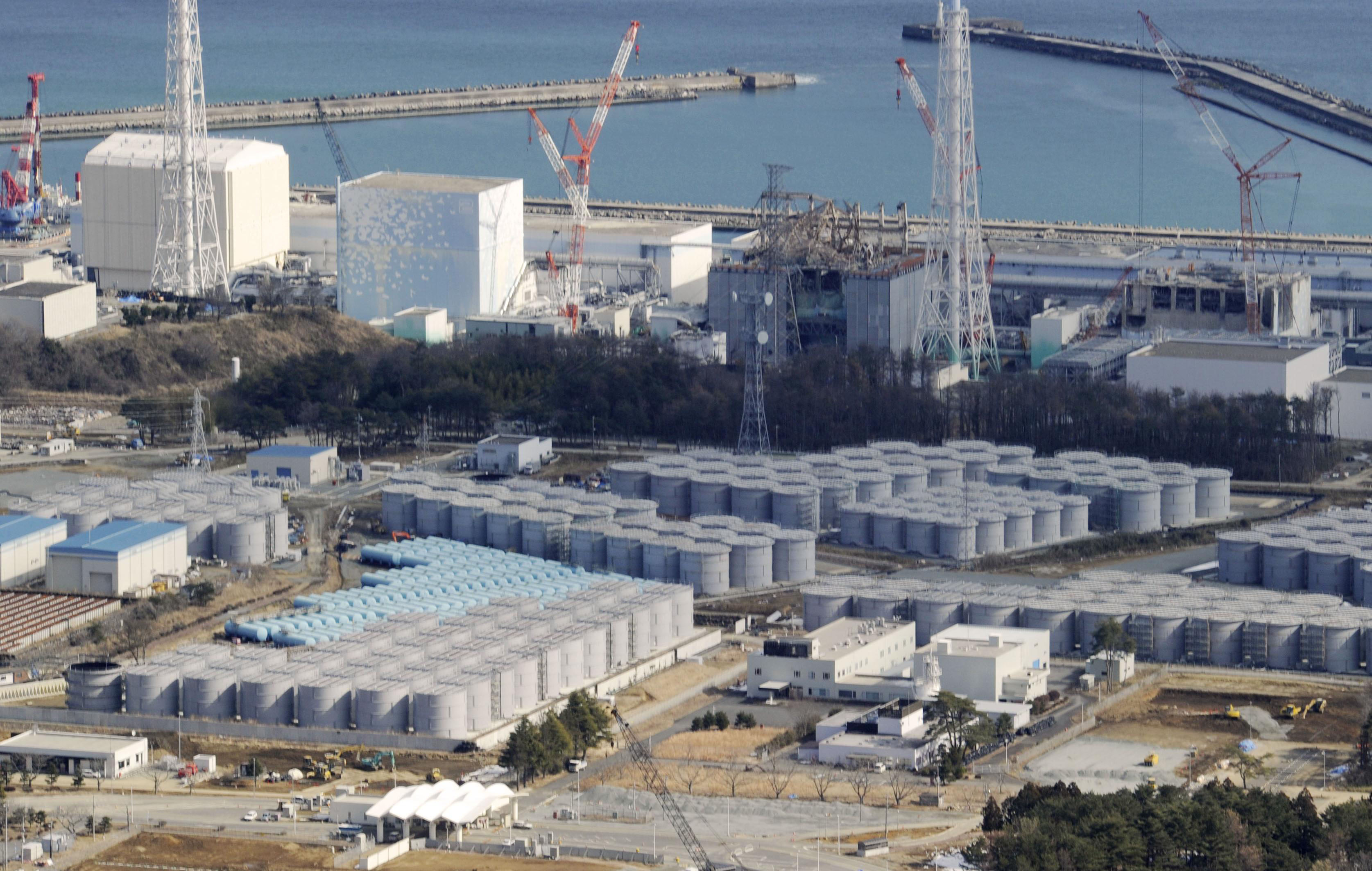 Multitude of problems: Tanks (foreground) containing radioactive water and reactor buildings (background) at the Fukushima No. 1 nuclear plant are photographed in February. | KYODO