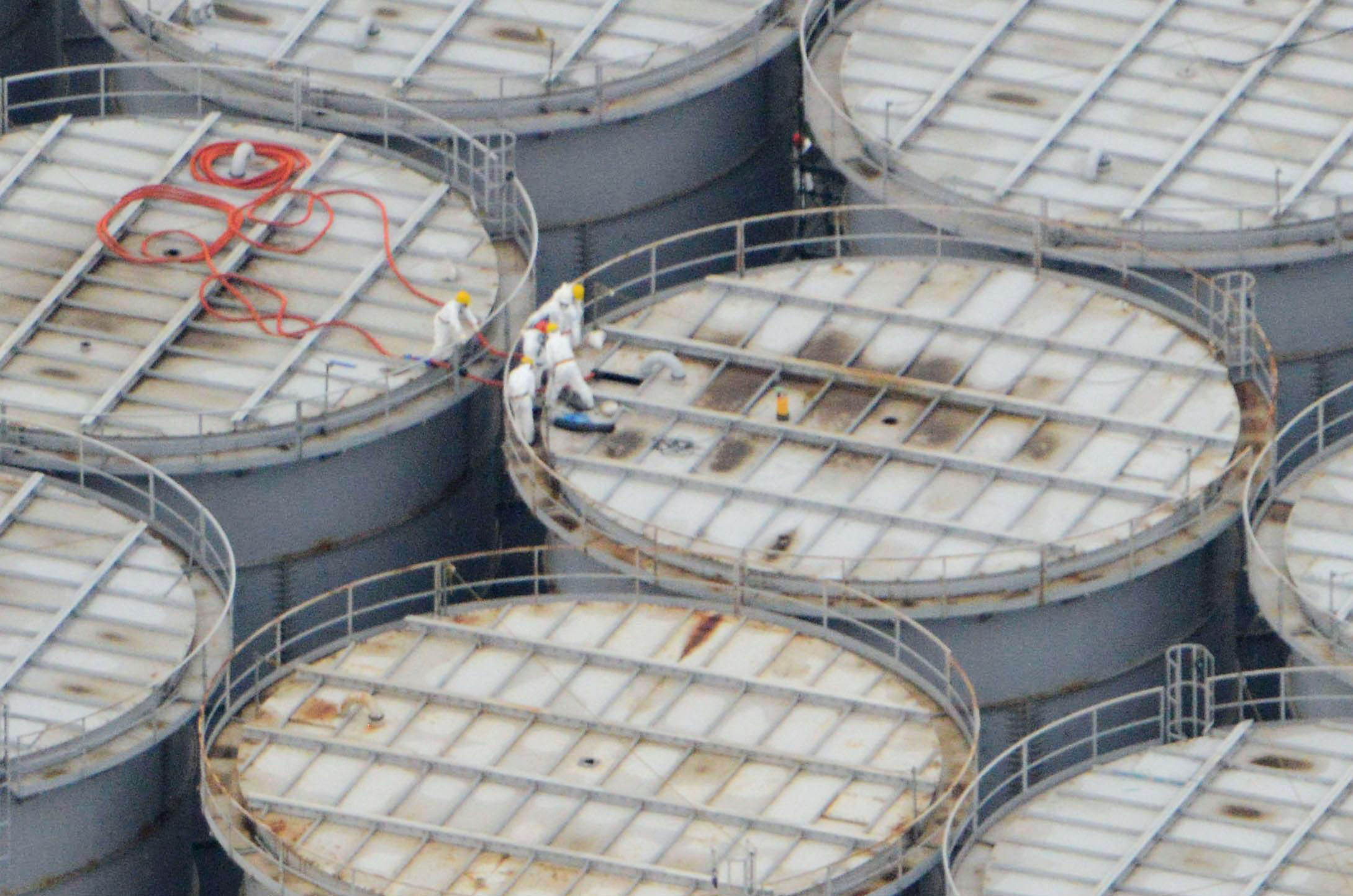 Water woes: Workers stand atop a tank for highly radioactive water at the Fukushima No. 1 nuclear power complex  Tuesday, where one container was found to have leaked 300 tons of water the same day. | KYODO