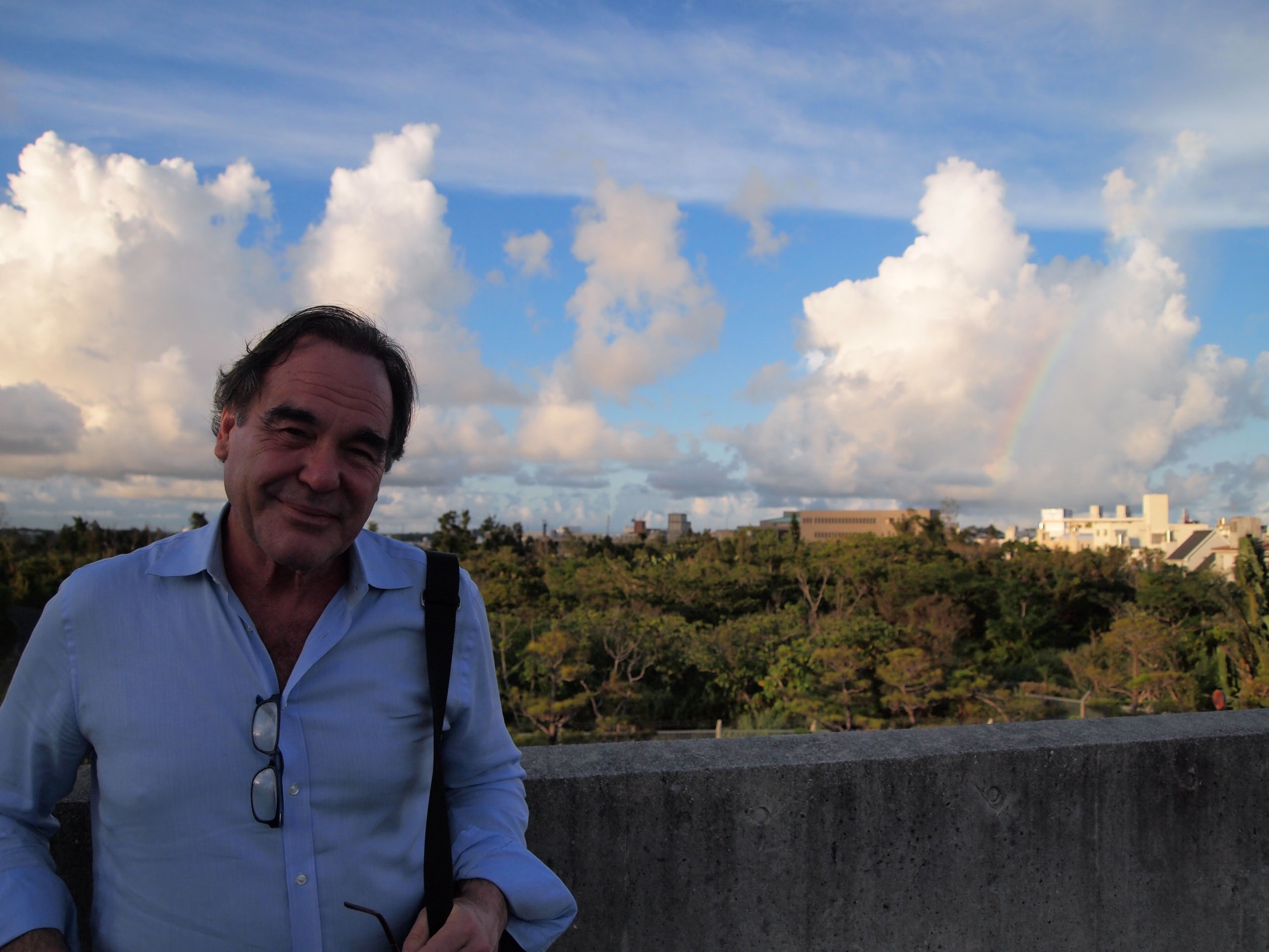 Tour of duty: A rainbow breaks through the clouds as American film director Oliver Stone stands on the rooftop of Sakima Art Museum in Ginowan, Okinawa, on Aug. 13. | JON MITCHELL