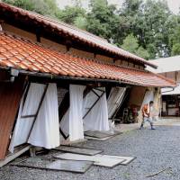 Holding on: A house tilts after being hit by a mudslide Saturday in Hamada, Shimane Prefecture, where more than 36,000 residents were advised to evacuate due to torrential rain. Shimane residents urged to evacuate amid heavy rain