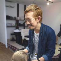 A little off the top: Mitsumasa Kanayama attends to a customer at his hair salon in Katsushika Ward, Tokyo, in June. | KYODO