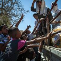 Winning young minds: Members of an Islamist rebel group distribute toys and other treats to children at a public park in the Islamic State of Iraq and the Levant stronghold of Raqqah on  Thursday. | AFP-JIJI