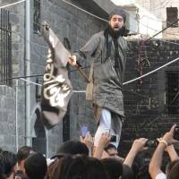 Fuel to the fire: A Syrian waves an Islamist flag at a protest against President Bashar Assad\'s regime in Homs on Aug. 8. | AFP-JIJI