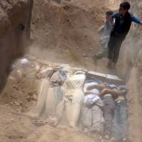 Massacre: This image from a video uploaded on YouTube by the Local Committee of Arbeen allegedly shows Syrians burying victims of a toxic gas attack by pro-government forces in eastern Ghouta and Zamalka, on the outskirts of Damascus. | AFP-JIJI