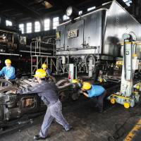 Workers disassemble a Type C57 steam locomotive at the Umekoji train yard in the city of Kyoto on Tuesday ahead of an overhaul. Work on the engine, which is still used to transport tourists and train buffs on special occasions in Yamaguchi Prefecture, is expected to be finished by next June. | KYODO