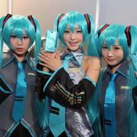 Blue-haired girls dressed as virtual pop star Hatsune Miku show off a limited version of Sony\'s Experia smartphone based on the hugely popular \"vocaloid\" voice-synthesizing app Thursday at the annual Tokyo Game Show at the Makuhari Messe convention hall in Chiba. The event opens to the public this weekend. | YOSHIAKI MIURA