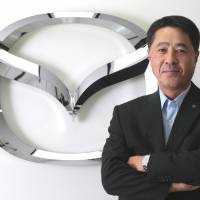 Export-oriented: Masamichi Kogai, president and chief executive officer of Mazda Motor Corp., poses in front of the company\'s logo in Tokyo last Friday. | BLOOMBERG