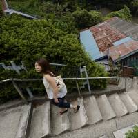 A young woman climbs a concrete stairway beside houses in the same area last month. Vacant homes highlight hole in 'Abenomics'