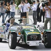 Off to the races: Senior Vice Industry Minister Isshu Sugawara (left) and Tadashi Tateuchi, head of the Japan Electric  Vehicle Club, ride a British Caterham Super Seven sports car that runs on electricity in Tokyo on Tuesday. | KYODO