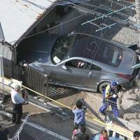 Inexperienced driver: A Nissan Fairlady Z is seen slammed into a garage after it plowed into a group of five elementary school children Tuesday morning in Yawata, Kyoto Prefecture. The driver, an 18-year-old male, reportedly told police he was going too fast around a bend. | KYODO