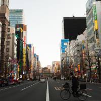 Bike this way: A man on a bicycle crosses a street in Tokyo\'s Akihabara district. The police are warning cyclists to stick to the left side of the road from now or face jail time and other penalties under a recent revision to the traffic law. | BLOOMBERG