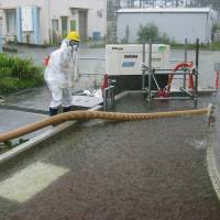 Rain, rain, go away: A worker pumps out radioactive water accumulating inside the barriers around a leaky coolant storage tank at the Fukushima No. 1 nuclear plant Sunday, the day before Typhoon Man-yi swept through Honshu, including the Tohoku region. 
 | TEPCO/KYODO