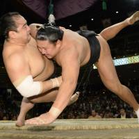 Flying tackle: Kyokutenho (right) takes down Aminishiki at the Autumn Grand Sumo Tournament on Monday. | KYODO