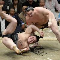 Live to fight another day: Hakuho (right) throws Harumafuji on the final day of the Autumn Grand Sumo Tournament on Sunday. Harumafuji finished with a 10-5 record. | KYODO
