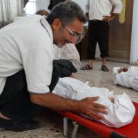 Misconduct of war: A Syrian weeps over the body of one of his children killed during an alleged toxic gas attack by pro-government forces in the Damascus suburb of eastern Ghouta in this photo released by the opposition Shaam News Network on Aug. 23. | AFP-JIJI