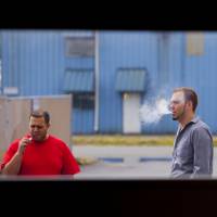 Vapor gets in your eyes: Two men smoke e-cigarettes on a work break. E-cigarettes are popular, but do they really work?