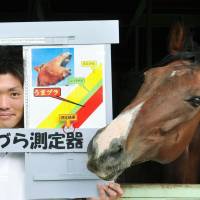 A worker at Mother Farm in Futtsu, Chiba Prefecture, measures how \"horse-faced\" he is using a special gauge. The farm will hold a humorous event each weekend until Nov. 24 for tourists who want to see how they measure up to the animals. The person whose face is longest will win a certificate and a carrot. | MOTHER FARM/KYODO