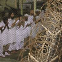 Detained: In this photo reviewed and approved by the U.S. military, detainees pray before dawn near a razor-wire fence at the U.S. Navy\'s Guantanamo Bay prison in May 2009. | AP