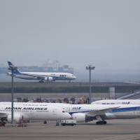 Coveted slots: A Boeing 787 Dreamliner operated by All Nippon Airways Co. lands at Haneda airport in Tokyo in late May. Japan Airlines Co. and ANA Holdings Inc. are fighting over additional slots at the airport, a dispute that is starting to include global airline partnerships. | BLOOMBERG