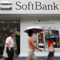 Wrong number: Pedestrians walk past a SoftBank Corp. store in Tokyo. The mobile phone company has been hit by a new scandal centered on its erroneous credit-rating of its customers. | BLOOMBERG