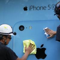 High hopes: Workers prepare a window display for the iPhone 5C outside an NTT DoCoMo store in Tokyo on Sept. 20. | BLOOMBERG
