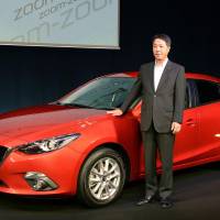 Newcomer: Mazda Motor Corp. President Masamichi Kogai stands by the hybrid version of the Axela compact in Tokyo on Wednesday. | KYODO