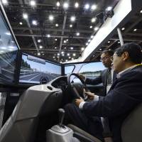 In for a spin: A visitor tries out a Honda Motor Co. driving simulator at the ITS World Congress Tokyo 2013 at Tokyo Big Sight in Koto Ward on Tuesday. | BLOOMBERG