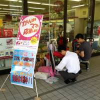 Added convenience: A father with a baby in Minato Ward signs up for the Smart Kitchen home delivery service targeting working parents that convenience store Lawson Inc. introduced in January. | MAMI MARUKO