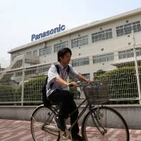 Picking up speed: A man rides past Panasonic\'s headquarters in Kadoma, Osaka Prefecture, on July 31. | BLOOMBERG