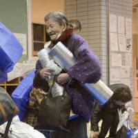 An elderly woman is relieved and leaves a shelter on Saturday evening after the evacuation order and advisory were lifted. | KYODO