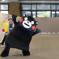 Kumamon, the popular mascot of Kumamoto Prefecture, performs a vigorous dance Monday for Emperor Akihito and Empress Michiko when the Imperial Couple paid a visit to the prefectural government building. | KYODO