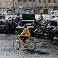 Never-ending detail: Baghdad municipal workers clear debris while citizens inspect the site of a car bomb attack in the Sha\'ab neighborhood Sunday, after insurgents unleashed a new wave of bombings in Shiite neighborhoods in the Iraqi capital, killing and wounding dozens | AP