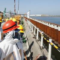Quick fix: Prime Minister Shinzo Abe (right) looks at an impervious wall made of steel pipe sheet installed along the shore of Tokyo Electric Power Co.\'s Fukushima No. 1 nuclear power plant Sept. 19 | BLOOMBERG