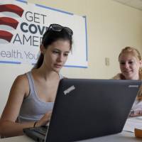 Roll up, sign up: A woman receives help signing up for the Affordable Care Act from a volunteer with Enroll America, a private nonprofit organization running a grass-roots campaign to encourage people to sign up for health care, in Tampa, Florida, on Tuesday. | AP