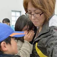 Yukiko Hirakawa greets her two children at Okada Port on Oshima Island on Sunday morning as they returned from Yokohama, where they took shelter from Typhoon Francisco on Wednesday. The evacuation order has since been lifted for all residents. | KYODO