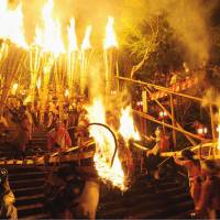 Men carry torches during the Kurama Fire Festival on Tuesday evening in Sakyo Ward, Kyoto. Some 500 torches, the largest measuring 3.5 meters in length and weighing 100 kg, lit up the sky during the annual event, which dates to 940. | KYODO