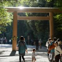 Visitors walk toward the Inner Ise Shrine in Mie Prefecture on Thursday morning to pray at the new shrine building after its deity was transferred from the old building Wednesday evening in the Shikinen Sengu ceremony. The inner and outer shrines are built anew every 20 years, and enshrined objects are relocated to the new buildings. | KYODO