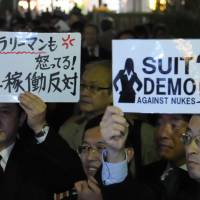 Hot under the collar: A man (left) holds up a sign reading \"Salaried workers are angry! No restart of nuclear power plants!\" during the Wednesday evening Suit Demo anti-nuke demonstration in Tokyo. | SATOKO KAWASAKI