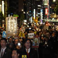 Rally with dress code?: Men and women walk through the Shinbashi district in Tokyo\'s Chiyoda Ward Wednesday evening while participating in the Suit Demo anti-nuclear demonstration. | SATOKO KAWASAKI