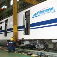 A Central Japan Railway Co. (JR Tokai) worker checks an upgraded N700-series shinkansen at the train yard in Hamamatsu, Shizuoka Prefecture, Monday. The latest upgrade will equip hundreds of the old N700 series cars with the advanced braking systems installed in the new N700A series, JR Tokai said. | KYODO