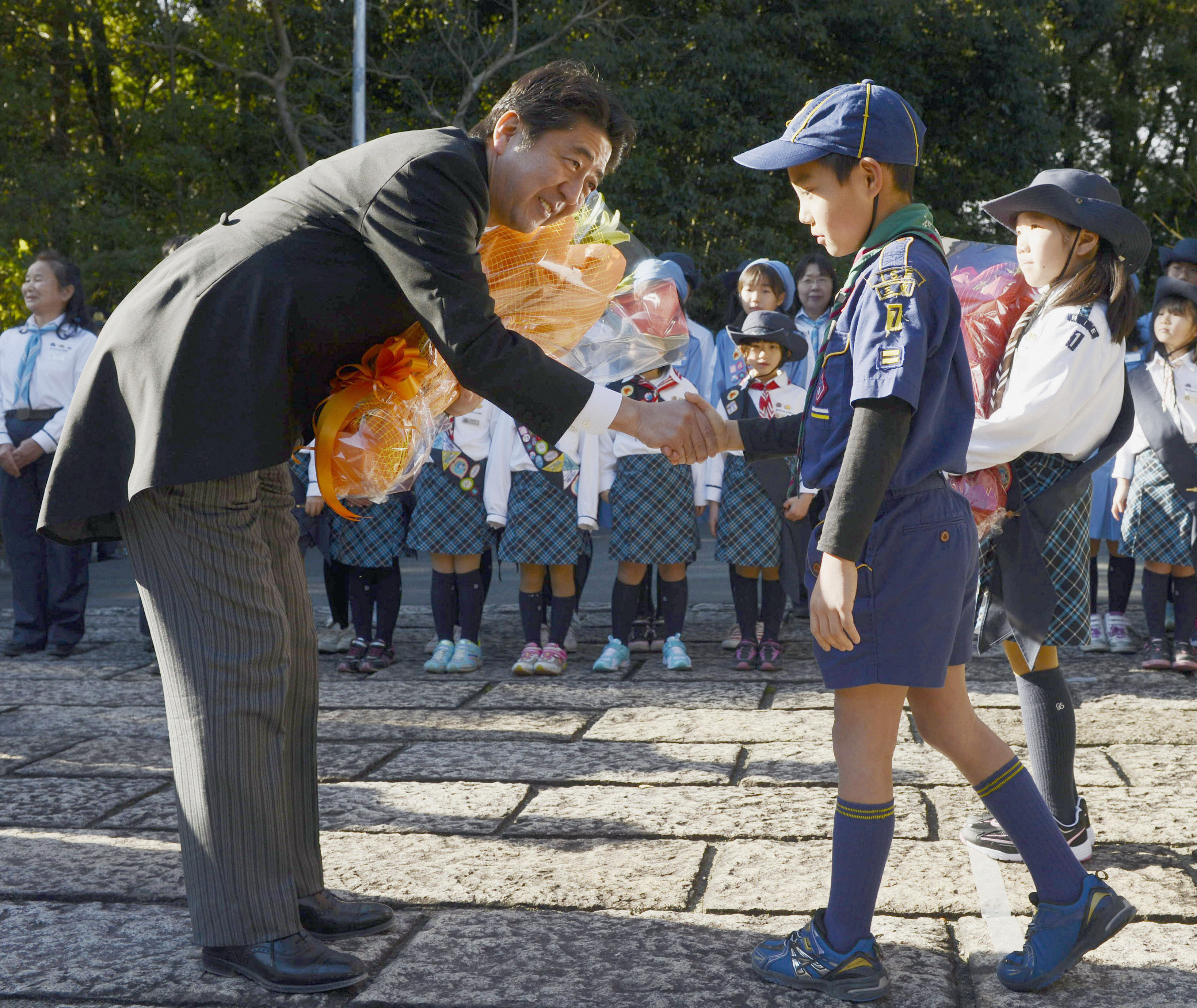 Prime Minister Shinzo Abe receives flowers from a child at ise Shrine, Mie Prefecture, in January. | KYODO
