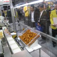 \"Bento\' bot: Visitors to Fanuc Corp.\'s booth observe a demonstration by a robot arm developed by the company for filling \"bento\" boxed meals at the International Robot Exhibition at Tokyo Big Sight on Thursday. The robot arm can grab a piece of fried chicken without crushing it and place it precisely in the right slot of a bento box. | ATSUSHI KODERA