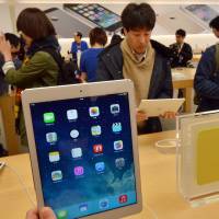 Must-have: Customers look over Apple\'s new iPad Air tablets at an Apple store in Tokyo on Friday. More than 300 customers lined up to buy the slimmed-down device, which debuted worldwide. | AFP-JIJI