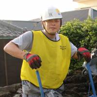 Muck raker?: Radio DJ Kosaku Mukai scoops mud out of damaged houses on Izu-Oshima Island last month. | KYODO