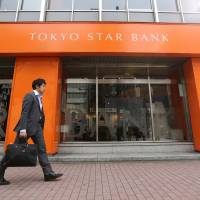Acquired: A pedestrian walks past a Tokyo Star Bank Ltd. branch in Tokyo on April 10. | BLOOMBERG