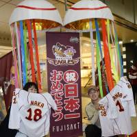 Stoked: Fans of the Tohoku Rakuten Golden Eagles hold up their favorite players\' jerseys in front of the Fujisaki department store in the city of Sendai on Monday before a special sale to celebrate the team\'s first Japan Series championship. | KYODO
